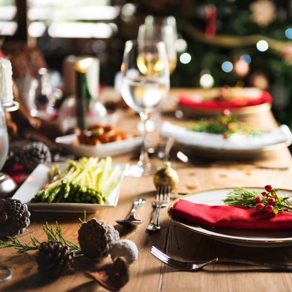 Festive dinner table set with plates of vegetables, wine glasses and Christmas decorations