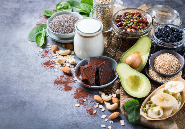 Assorted magnesium-rich foods including avocado, beans, chocolate, nuts and seeds