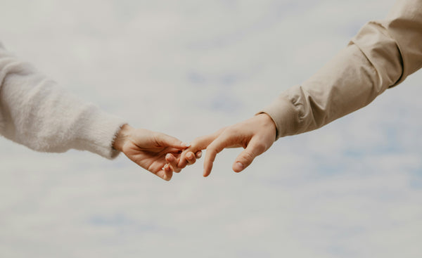 Close-up of two hands reaching toward each other with fingertips touching