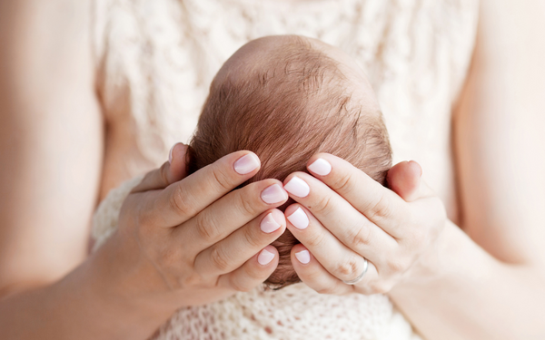 Close-up of hands cradling a newborn baby's head