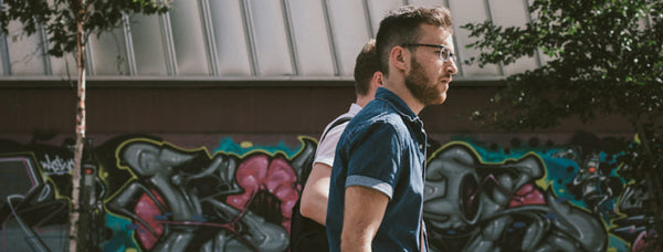 Young man walking past a colourful graffiti wall