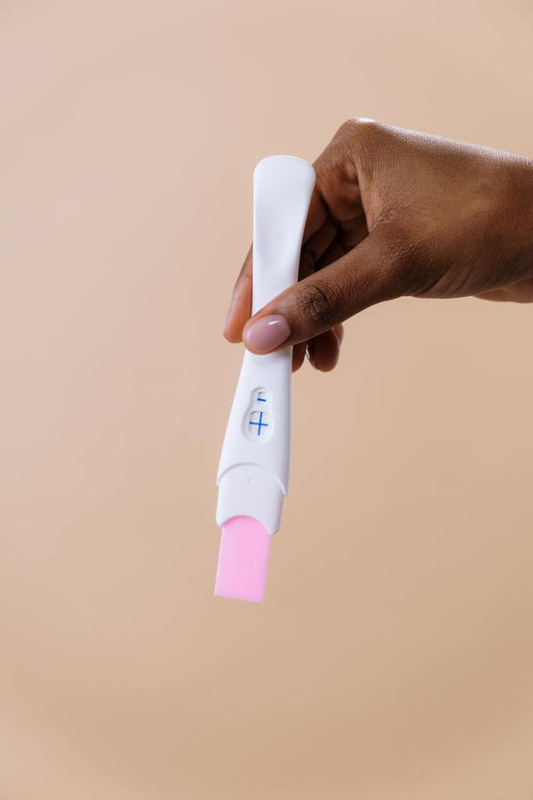 Hand holding a pregnancy test showing a positive result