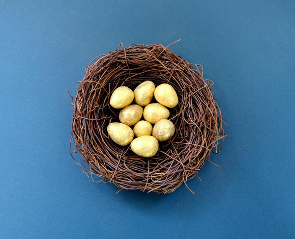 Golden decorative eggs nestled in a twig nest on a blue background