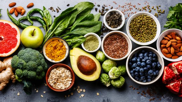 Overhead spread of fruits, vegetables, nuts and seeds including avocado, broccoli, blueberries and almonds