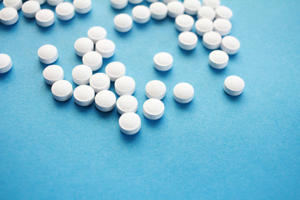 Close-up of small white round tablets scattered on a blue background