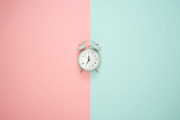 Vintage alarm clock centered against a pink and mint green split background