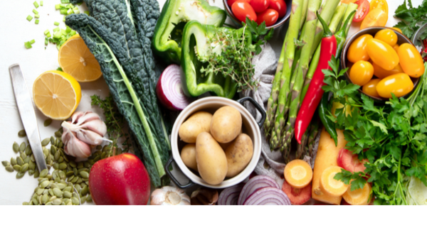Overhead view of assorted fresh vegetables including kale, peppers, asparagus, tomatoes and potatoes