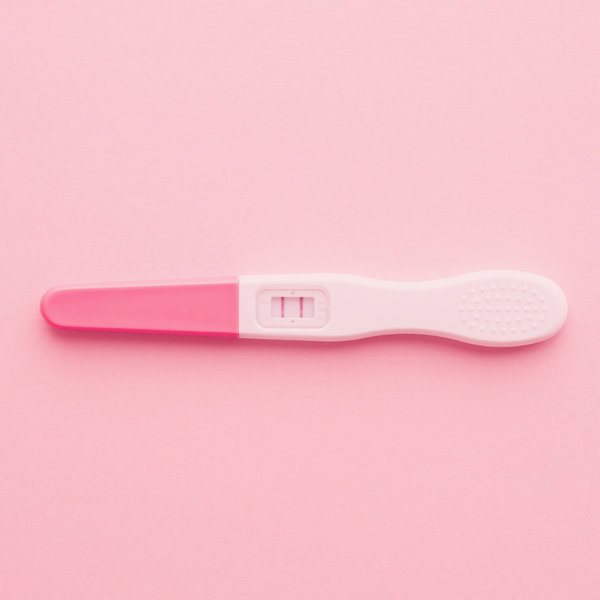 Pregnancy test showing a positive result on a pink background