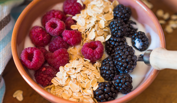 Bowl of yogurt topped with raspberries, blackberries and oats