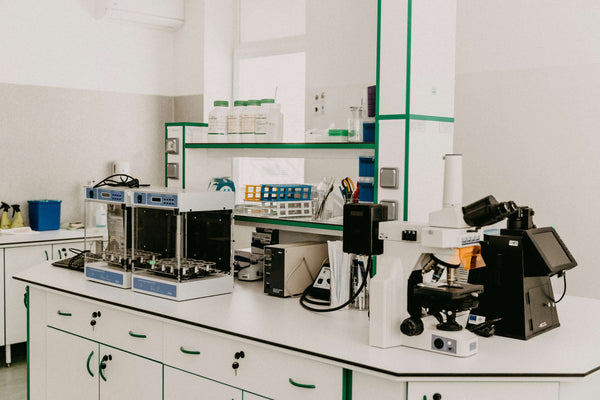 Gloved hand holding a test tube in a calm laboratory setting, representing independent supplement quality testing