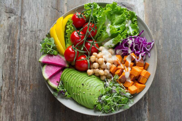 Overhead spread of fresh fruits, vegetables, nuts and seeds arranged on a table