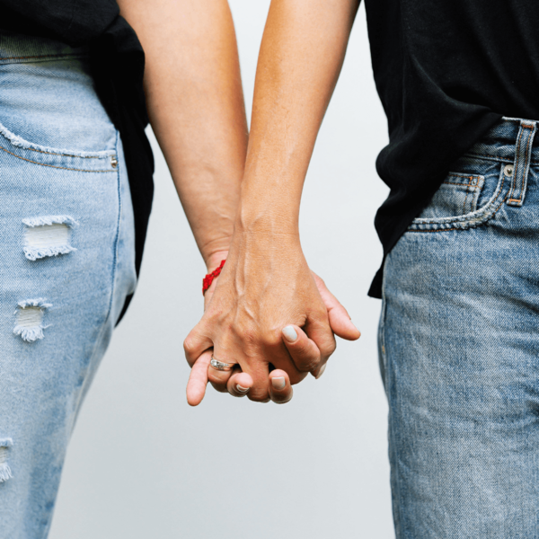 Close-up of a couple holding hands, one wearing a wedding ring