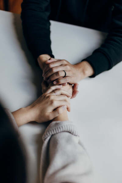 Close-up of two people's hands clasped together on a table