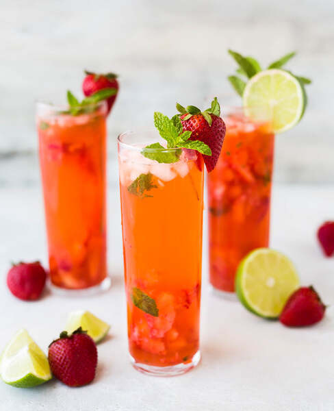 Three tall glasses of strawberry and lime mocktails garnished with mint