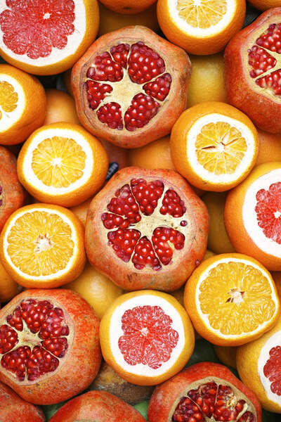 Overhead view of sliced pomegranates, oranges and grapefruits arranged closely together