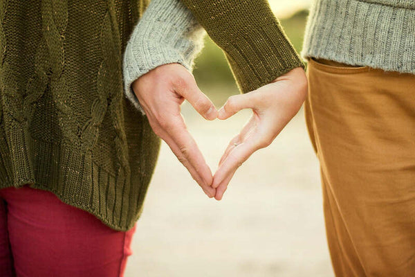 Close-up of two people's hands forming a heart shape together