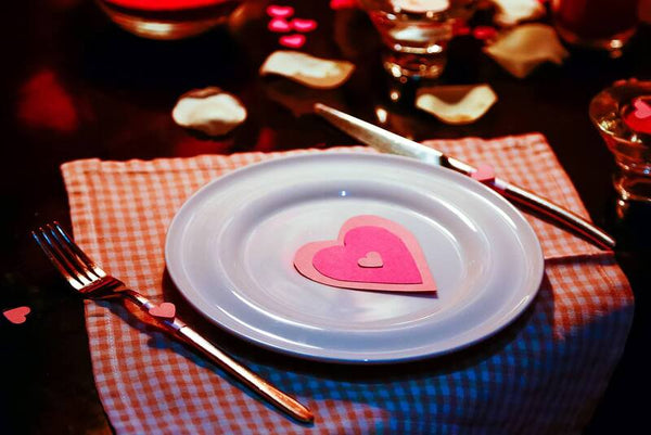 Table setting with a paper heart on a white plate and a gingham napkin