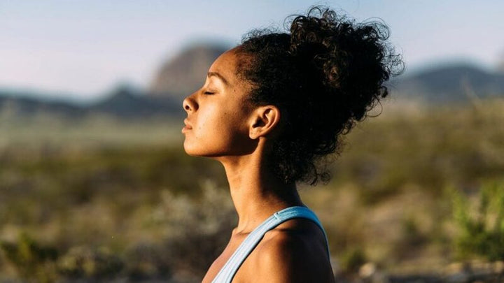 Woman with eyes closed standing outdoors in soft evening light