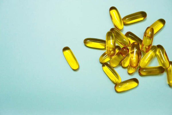 Close-up of yellow supplement capsules on a light blue background