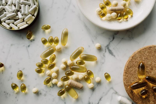 Scattered omega-3 capsules and supplement pills on a marble surface