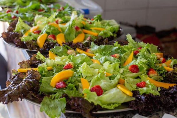 Platters of green salad topped with strawberries and mango slices