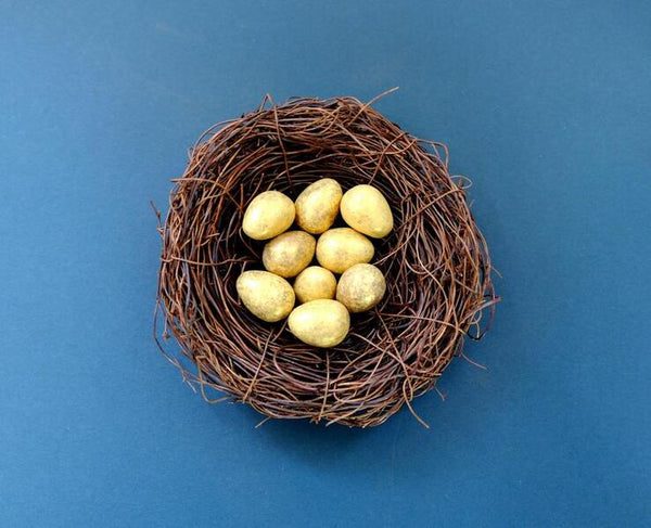 Golden decorative eggs nestled in a twig nest on a blue background