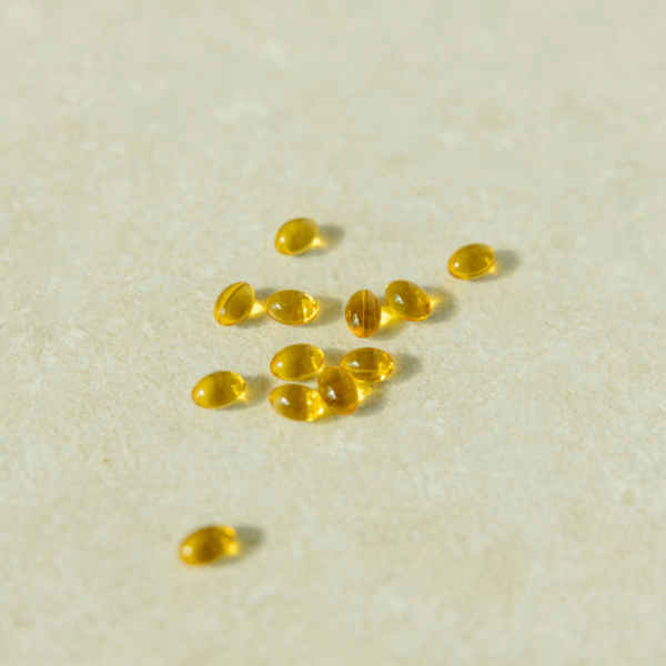 Scattered omega-3 fish oil capsules on a beige surface