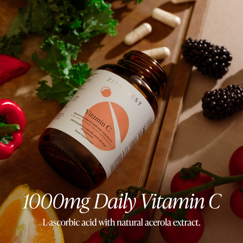 Vitamin C supplement bottle on a wooden surface with fresh fruits and vegetables.