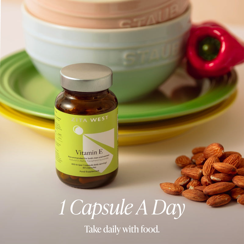 Vitamin E capsule bottle with almonds and a Staub pot in the background